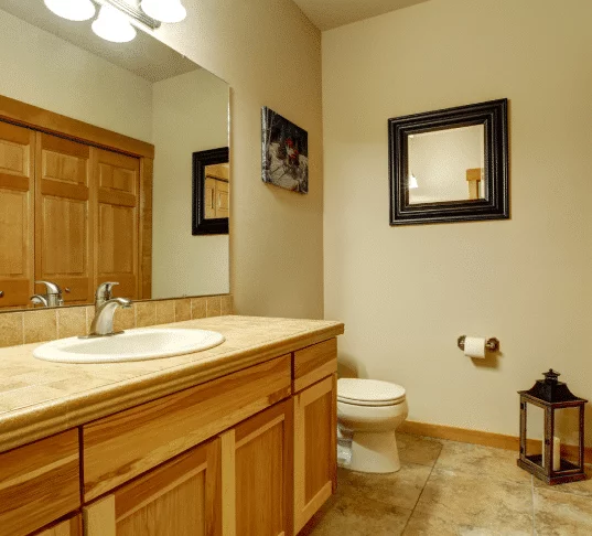 Modern bathroom interior with wood cabinets and tiled floor. Cost-effective design. Typical Bathroom Remodel Costs.