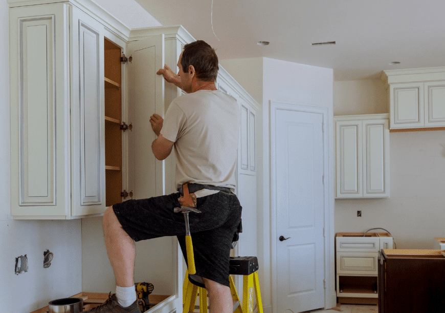 A guy is installing a shaker white cabinet. Cabinet renovation.