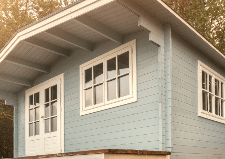 Cozy blue laneway house with white trim nestled in a natural setting, ideal for Burnaby living.