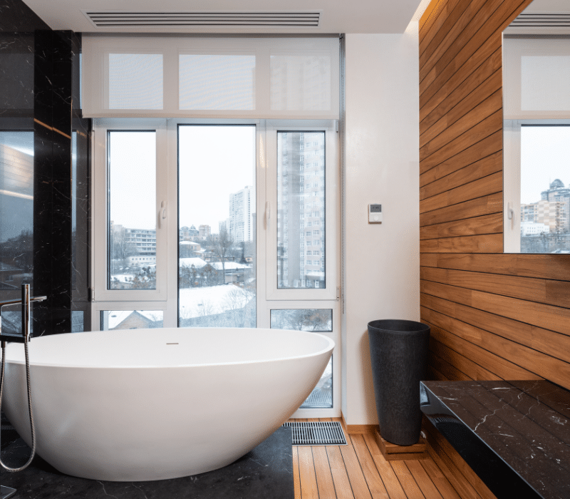 Modern bathroom with a freestanding tub, black marble accents, and warm wooden details, typical of the luxury designs found in bathroom showrooms.