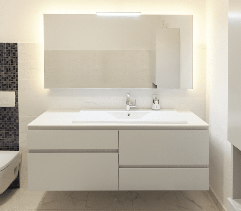 Minimalist bathroom vanity with sleek white cabinetry and a large mirror, reflecting the clean design available at vanity showrooms.