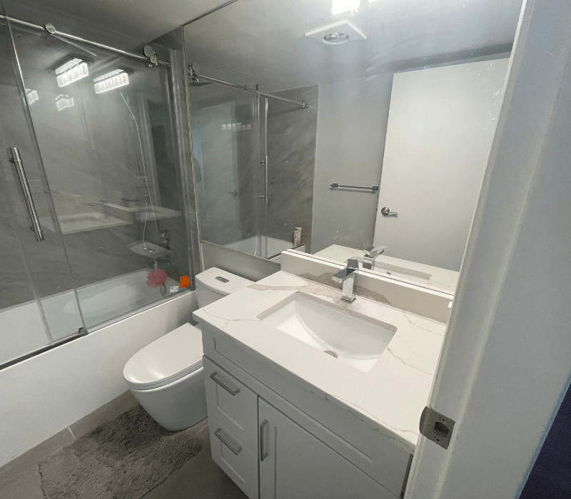 Modern bathroom with a glass-enclosed bathtub, white vanity, and sleek fixtures.