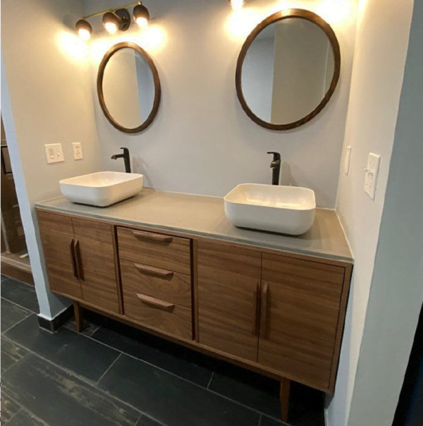 a freestanding double bathroom vanity with a walnut finish, featuring modern brass fixtures and large rectangular mirrors in a bright, stylish bathroom.