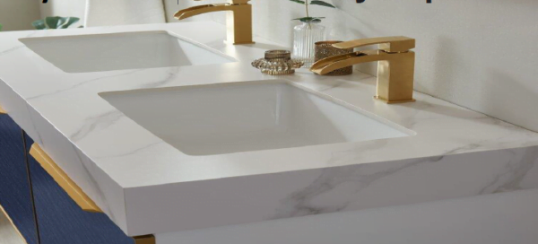 close-up of a granite double sink vanity top with gold faucets.