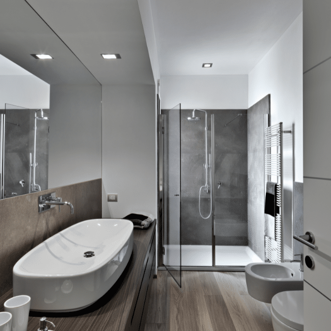 A stylish bathroom renovation in North Vancouver featuring a sleek vanity, glass shower, and contemporary dark tiles.