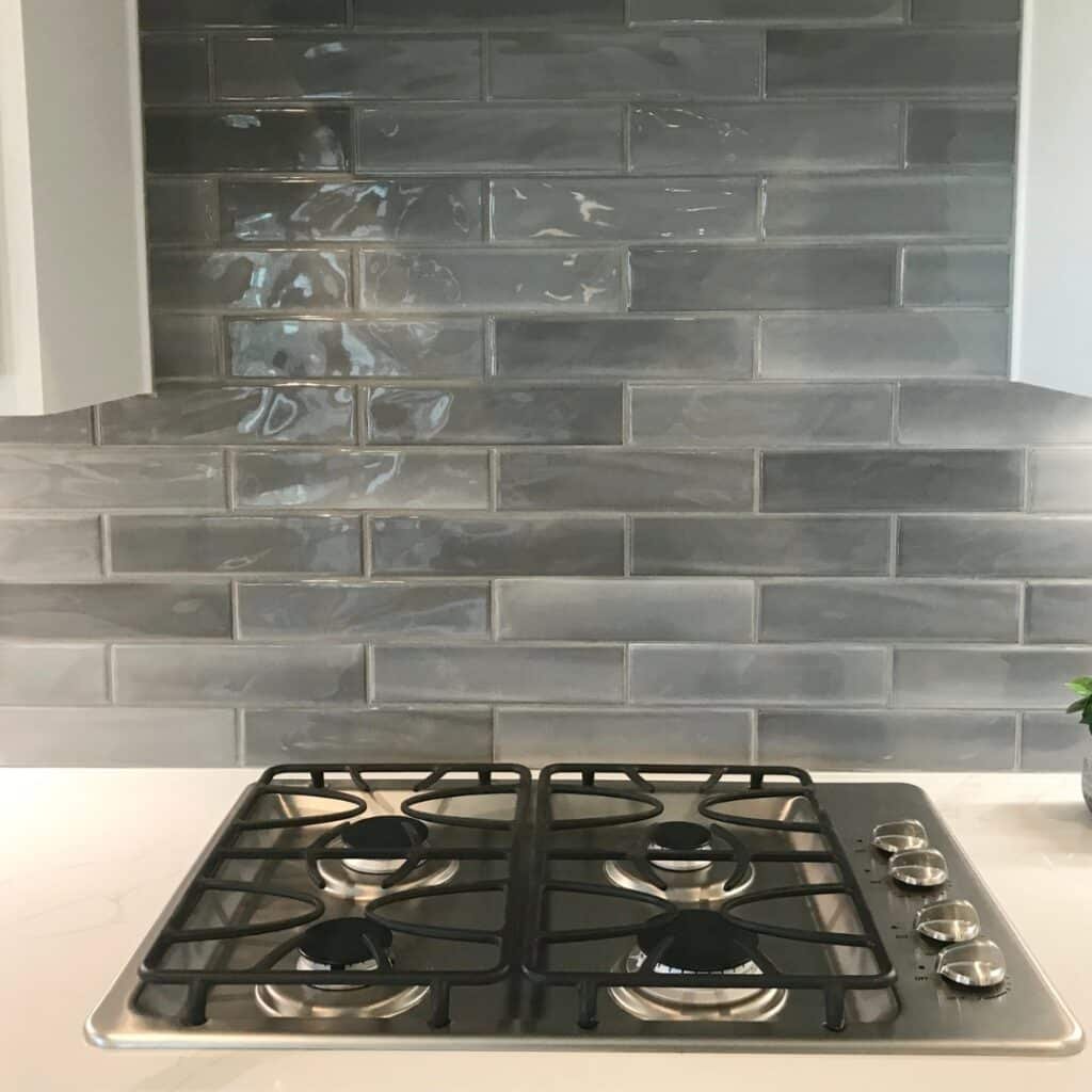 Kitchen Countertops and Backsplash vancouver: Modern kitchen with glossy gray subway tile backsplash and white quartz countertop featuring a stainless steel gas stove.