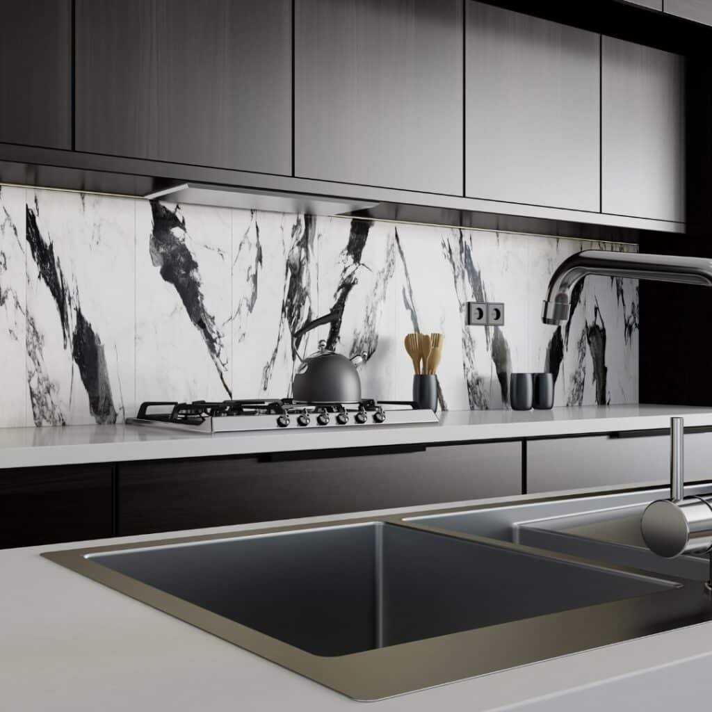 Modern kitchen with a white marble backsplash featuring bold black veining, sleek black cabinets, and a stainless steel sink.