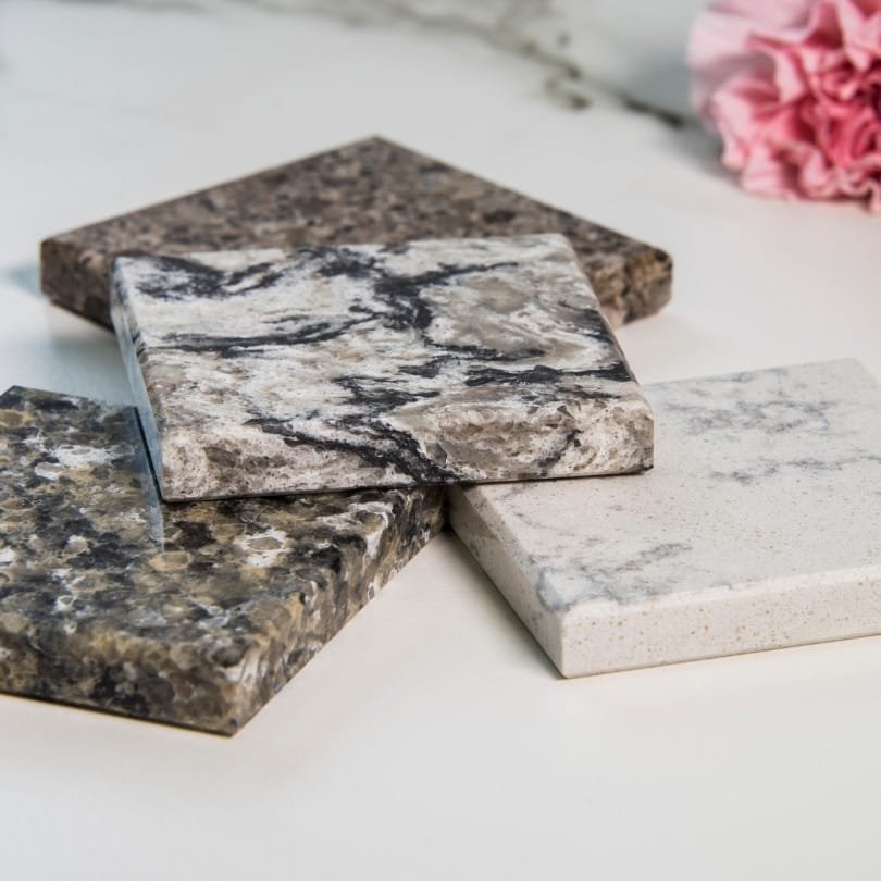 Variety of granite countertops samples in different colors and patterns displayed on a white surface.