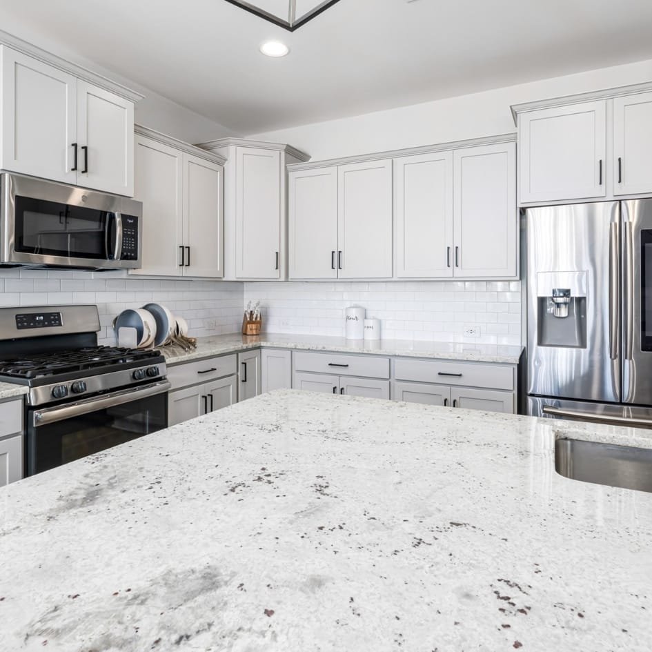 Modern kitchen with white granite countertops and sleek cabinetry.