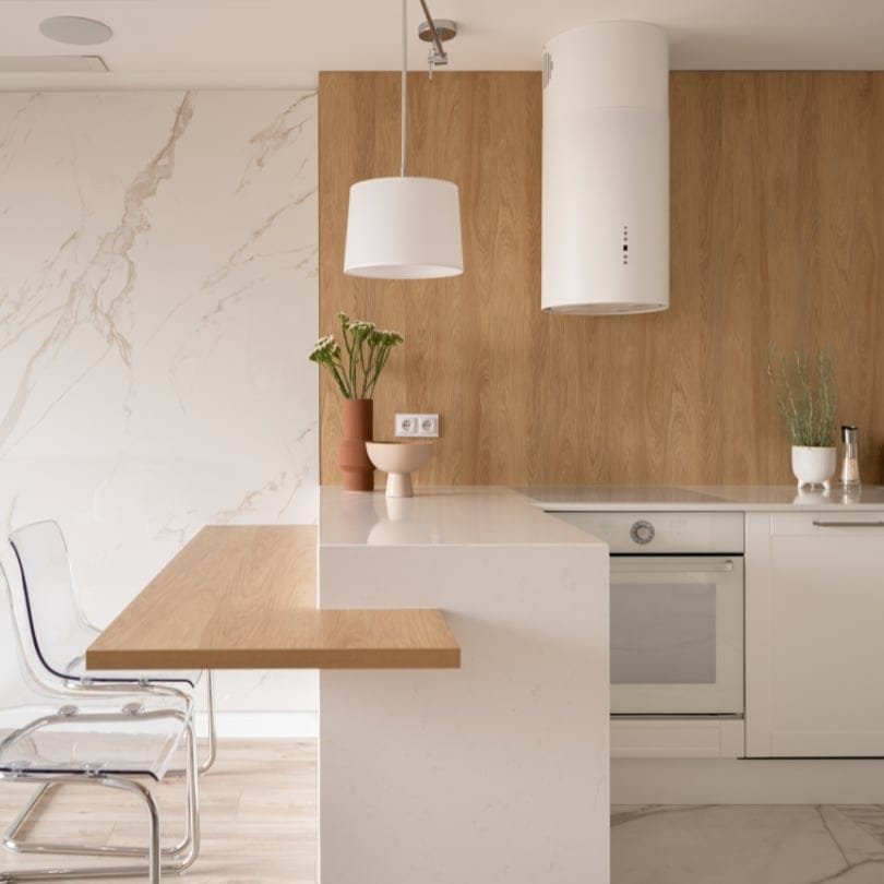 Bright kitchen renovation in North Vancouver featuring natural wood accents, white cabinets, and marble backsplash.