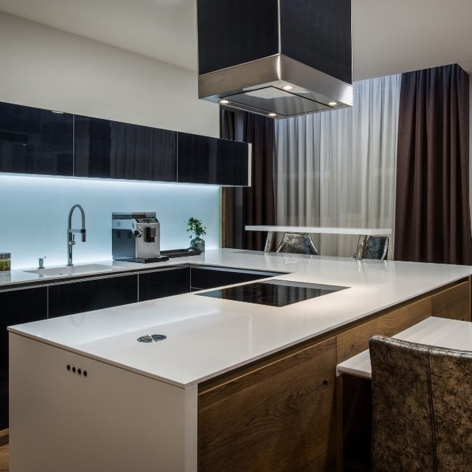 Modern kitchen with sleek black cabinets, white countertops, and a stylish island with integrated cooktop.