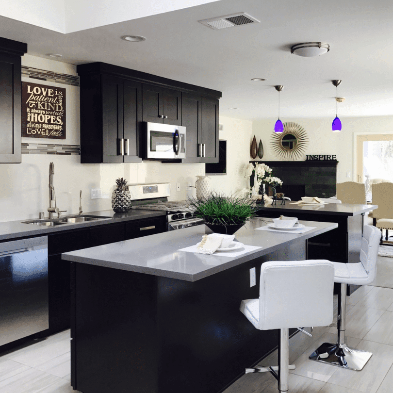 Modern kitchen renovation with dark cabinets, light countertops, and stylish pendant lighting. Elegant contrast design.