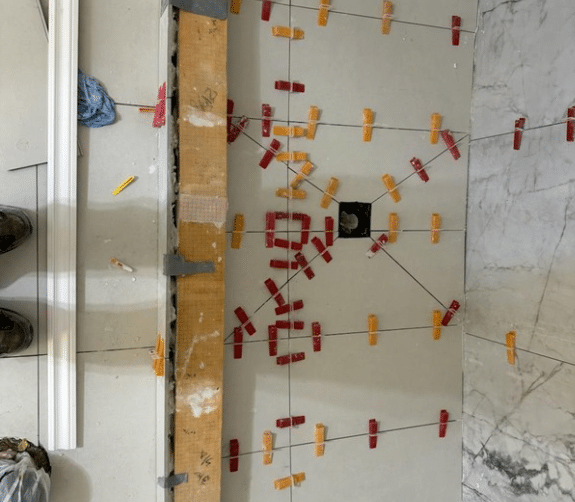 floor and tile installation process with spacers and leveling system in place.