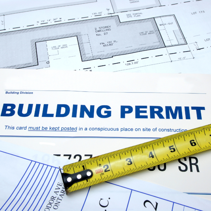 do i need a permit to remodel my kitchen A building permit and architectural plans, with a yellow measuring tape placed across them.