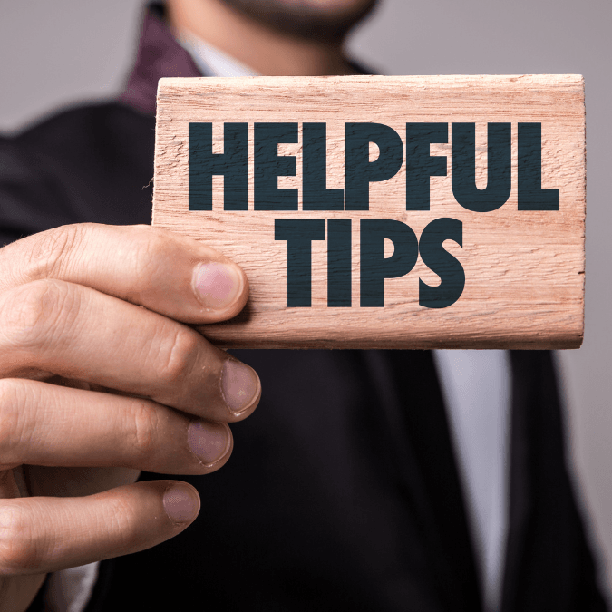 Close-up of a person holding a wooden sign that says 'Helpful Tips' for kitchen renovation advice.